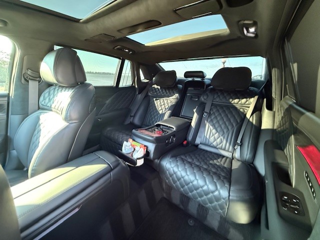 Businessman in a suit talking on phone inside a luxury car.